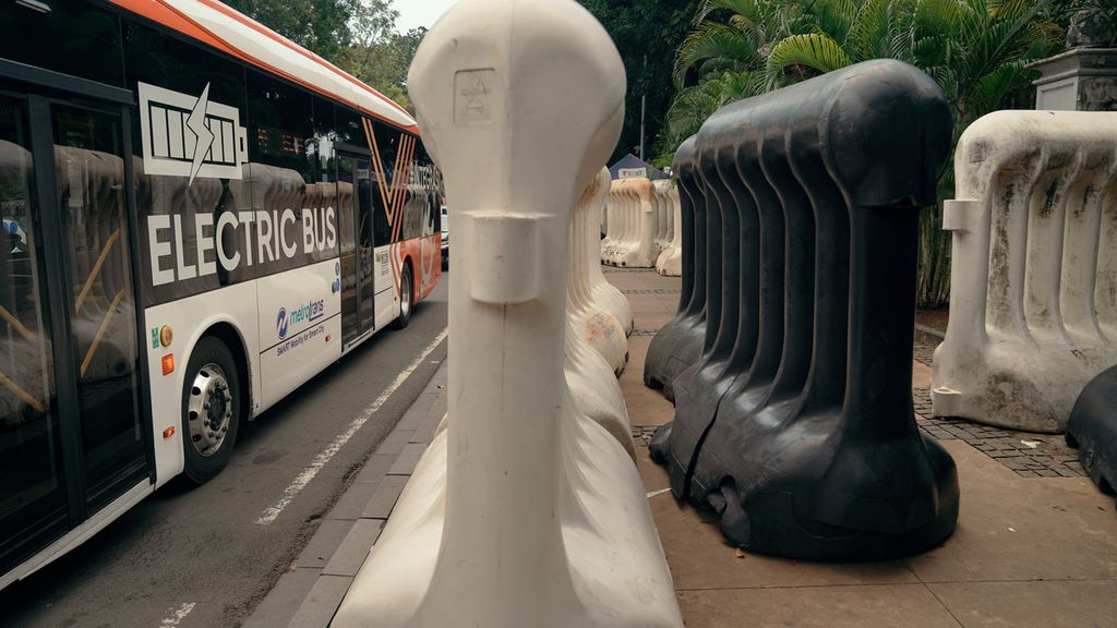 Bus listrik Transjakarta melintas di samping barikade di Jalan Medan Merdeka Barat, Jakarta Pusat, Senin (3/10/2022). PT Transportasi Jakarta (Transjakarta) menargetkan semua bus yang dioperasikan pada tahun 2030 adalah bus listrik. 