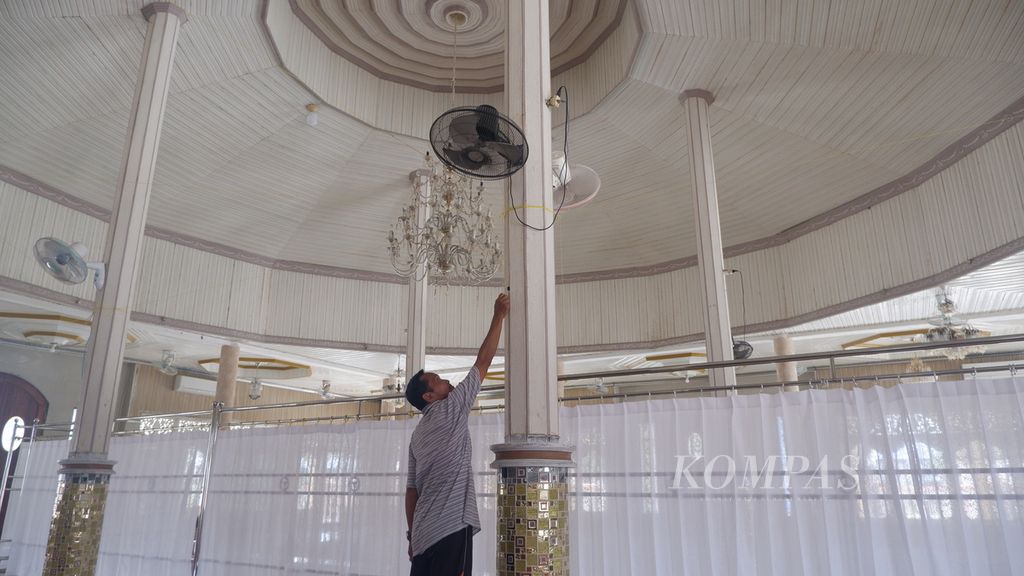 Suriansyah (57), marbot atau kaum masjid, menyalakan kipas angin di Masjid Al-Amin, Banua Anyar, Banjarmasin, Kalimantan Selatan, Kamis (21/3/2024).