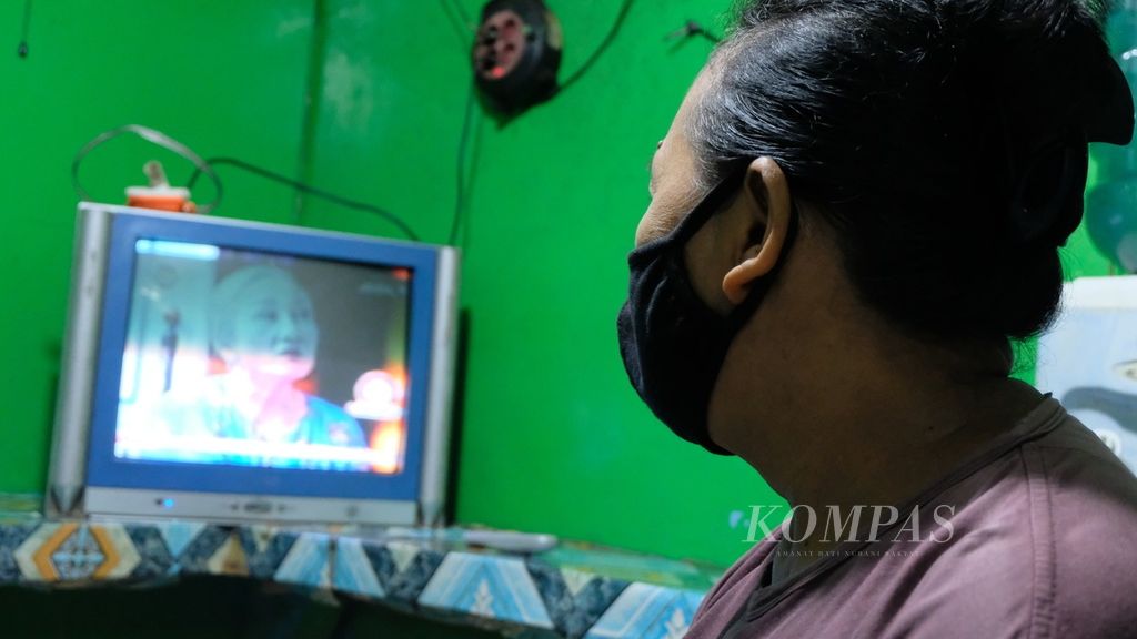 Seorang pedagang makanan menonton sinetron yang disiarkan di televisi, Senin (15/3/2021) di Jakarta. Sinetron jadi salah satu hiburan warga yang mudah diakses dan gratis.