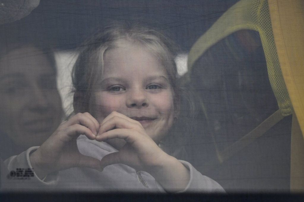 Seorang anak Ukraina membuat bentuk hati dengan tangannya saat dia berada di dalam bus yang melewati perbatasan Isaccea-Orlivka, di Romania, Jumat (25/3/2022). 