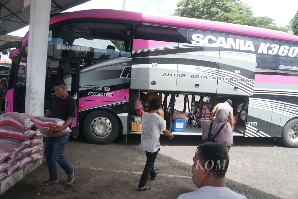 Para petugas Perusahaan Otobus Raja Trans menurunkan muatan dari bagasi bus, Senin (5/9/2022), di Terminal Malalayang, Manado, Sulawesi Utara.