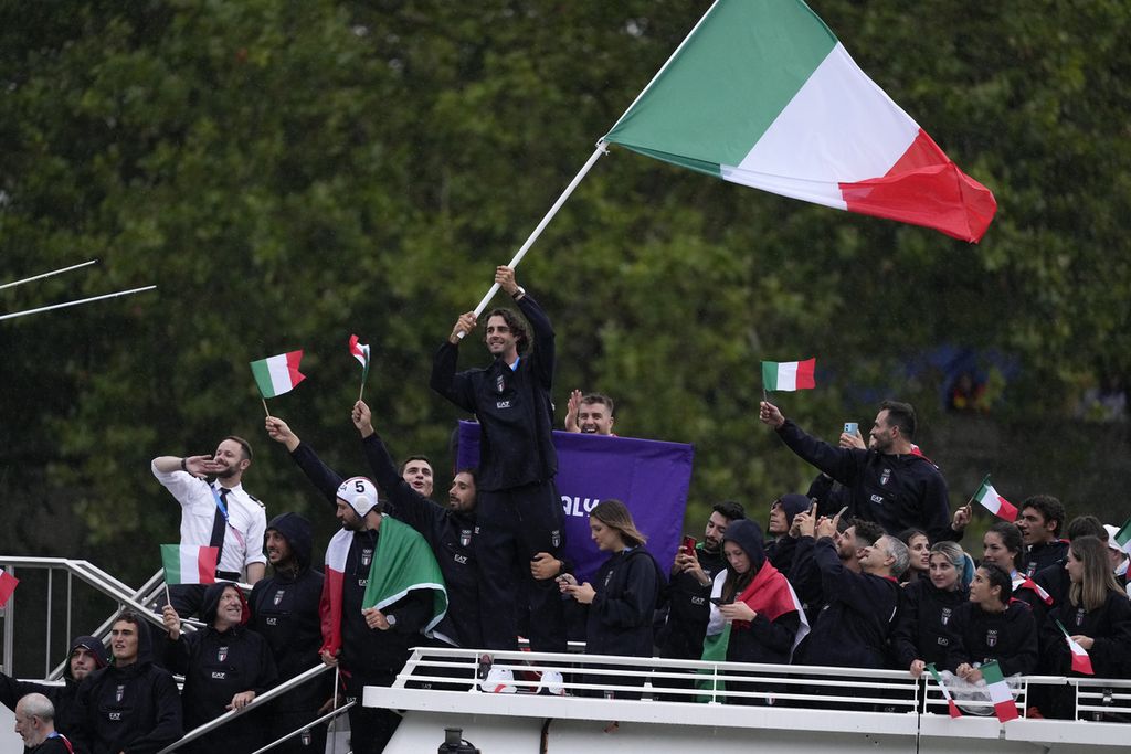 Atlet Italia Gianmarco Tamberi melambaikan bendera Italia saat defile atlet pada pembukaan Olimpiade Paris, 26 Juli 2024, di Sungai Seine, Paris, Perancis. Tamberi kehilangan cincin kawinnya saat pawai ini.