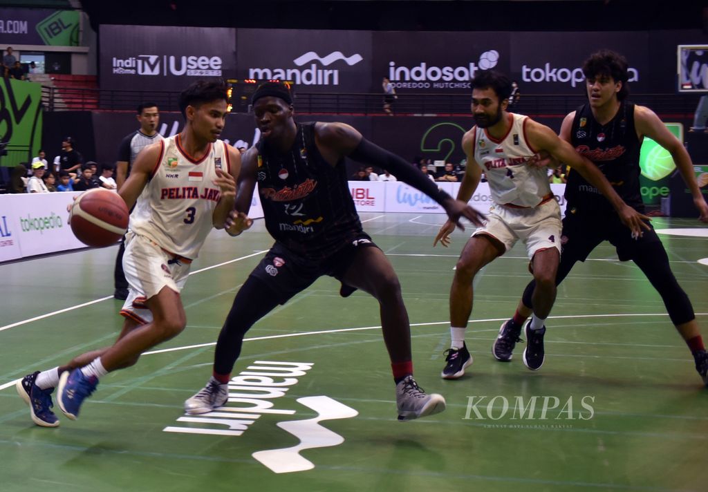 <i>Guard</i> Pelita Jaya Bakrie Jakarta, Yesaya Alessandro Saudale (white), tried to break through the Indonesian Patriots' <i> forward</i> guard, Dame Diagne, in the sixth series match of the Indonesian Basketball League (IBL) 2023 in Amongraga Sports Hall, Yogyakarta, Thursday (25/5/2023). Pelita Jaya eventually won 79-58 so they are firmly in third place with 36 points from 19 matches.