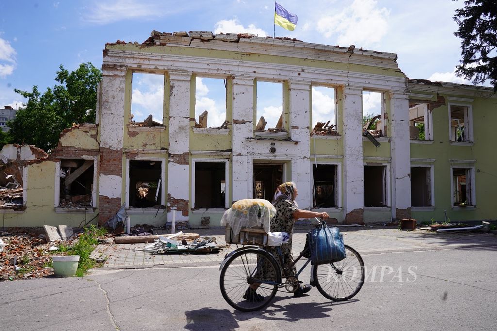 People pass in front of a building destroyed by a Russian missile in Okhtyrka, Sumy Province, Ukraine, Sunday (22/6/2022).