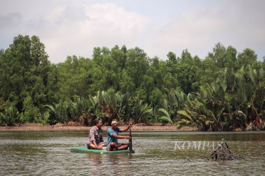 Sudarmin (53) bersama seorang pendamping dari Yayasan Biosfer Manusia memeriksa udang di tambaknya di Delta Mahakam, Kelurahan Muara Kembang, Kecamatan Muara Jawa, Kutai Kartanegara, Kalimantan Timur, pada Senin (4/7/2022) siang.