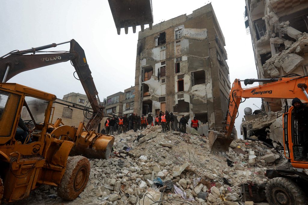 Machinery and rescuers shift through the rubble of a building during a search for survivors in Hama, following a deadly earthquake on February 6, 2023. - The Syrian government urged the international community to come to its aid after more than 850 people died in the country following a 7.8-magnitude earthquake in neighbouring Turkey. 