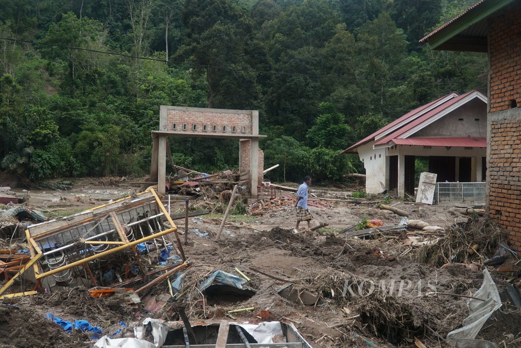 Warga melintas di sekitar rumah yang hancur diterjang banjir bandang di Kampung Batu Bala, Nagari Ganting Mudiak Utara Surantih, Kecamatan Sutera, Kabupaten Pesisir Selatan, Sumatera Barat, Selasa (12/3/2024).