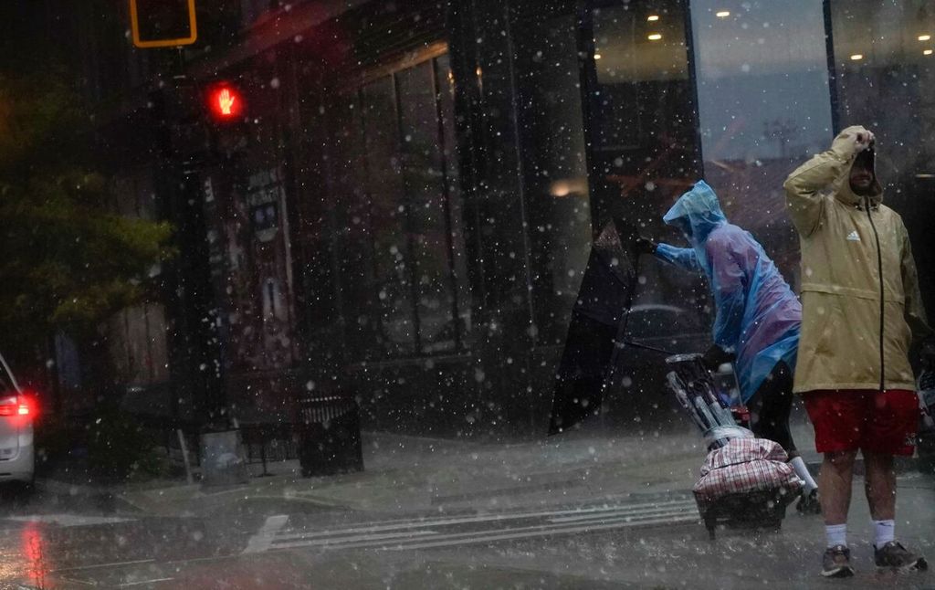 Sebuah payung tertiup ke luar saat seseorang menyeberang jalan saat terjadi badai di Washington, DC, pada Senin (7/8/2023). 