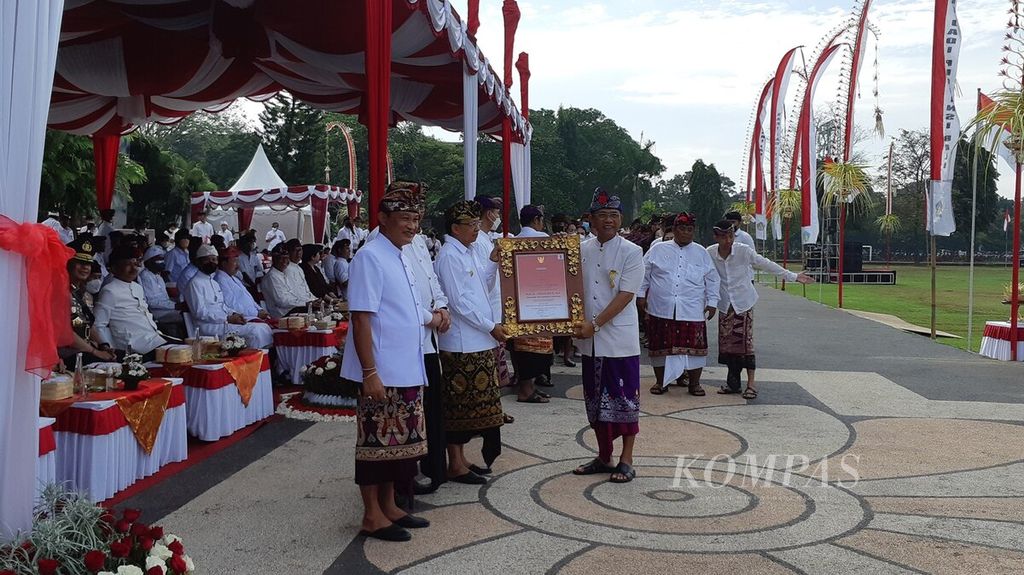 Gubernur Bali Wayan Koster menyerahkan piagam penghargaan Dharma Kusuma kepada akademisi dan seniman karawitan, I Wayan Rai (kanan), serangkaian dengan peringatan hari jadi ke-64 Provinsi Bali di Lapangan Puputan Margarana Niti Mandala Renon, Kota Denpasar, Minggu (14/8/2022).