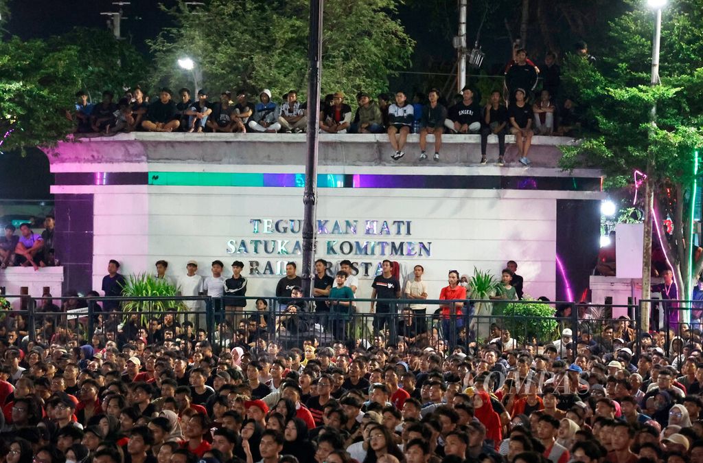 Audiences seek the best position, one of which requires climbing the fence, while watching the 2024 AFC U-23 Asia Cup match between Indonesia and Uzbekistan in the courtyard of the Semarang City Hall, Semarang, Central Java, on Monday (29/4/2024).