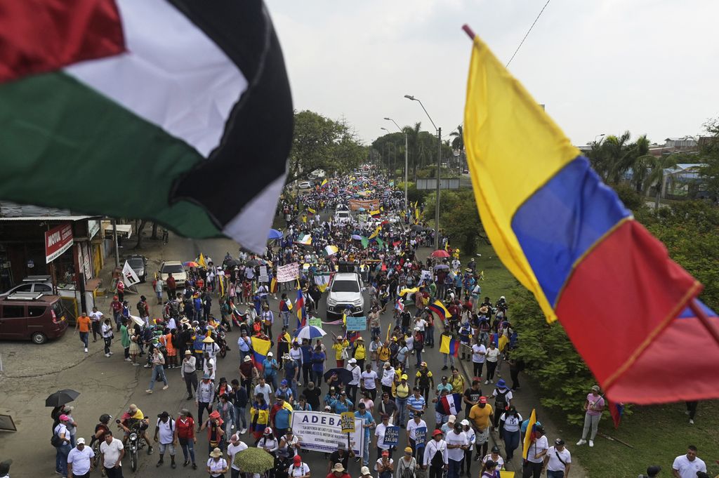 Warga ambil bagian dalam unjuk rasa Hari Buruh di Cali, Kolombia, 1 Mei 2024. Tampak bendera Kolombia dan Palestina berkibar. 