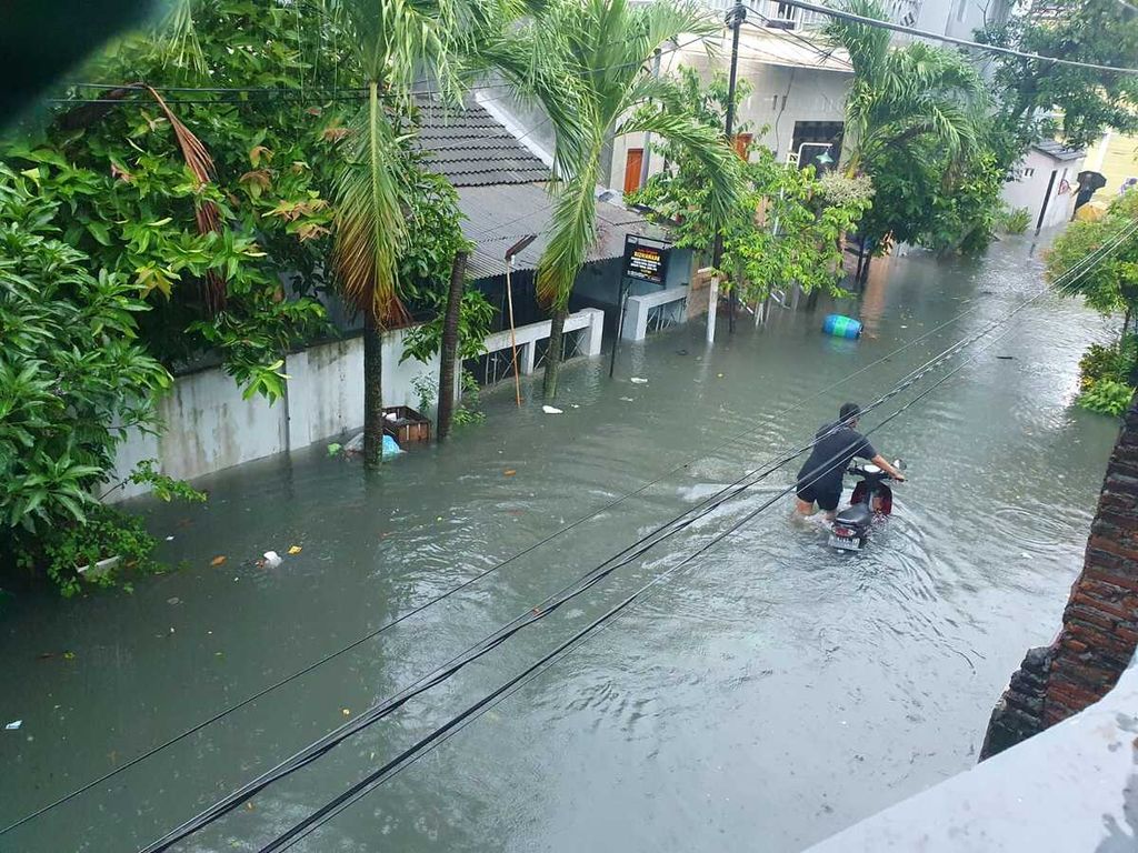 Warga mendorong kendaraannya yang terjebak banjir, Sabtu (31/12/2022), di Kelurahan Siwalan, Kecamatan Gayamsari, Kota Semarang, Jawa Tengah. Banjir dengan ketinggian sekitar 50 sentimeter itu membuat kendaraan yang nekat melintas di tengah genangan banjir mogok. 