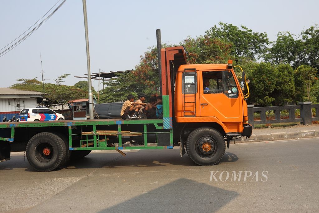 Sejumlah pelajar nekat menumpang truk kontainer yang melintas di Jalan Akses Marunda, Jakarta Utara, Rabu (18/9/2019). 