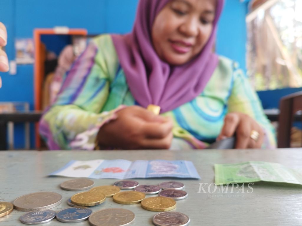 Muliyati (48) menunjukkan sejumlah mata uang ringgit, baik dalam bentuk uang kertas maupun koin, di Desa Aji Kuning, Kabupaten Nunukan, Kalimantan Utara, Sabtu (24/2/2024).