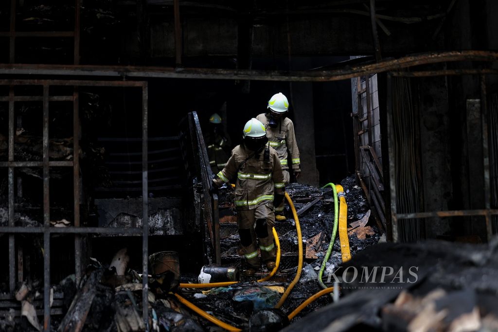 Petugas pemadam kebakaran melakukan pendinginan di toko bingkai yang terbakar di Jalan Mampang Prapatan, Jakarta Selatan, Jumat (19/4/2024). Kebakaran yang melanda toko bingkai di jalan tersebut menewaskan 7 orang dan 5 orang lainnya luka-luka. Ketujuh korban tewas tersebut diduga terjebak di dalam toko. Kebakaran terjadi pada Kamis (18/4/2024) pukul 19.30 WIB. 