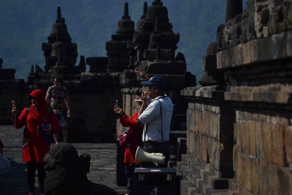 Pemandu wisata mengarahkan wisatawan pengunjung Candi Borobudur di Kabupaten Magelang, Jawa Tengah, Kamis (13/2/2020). 