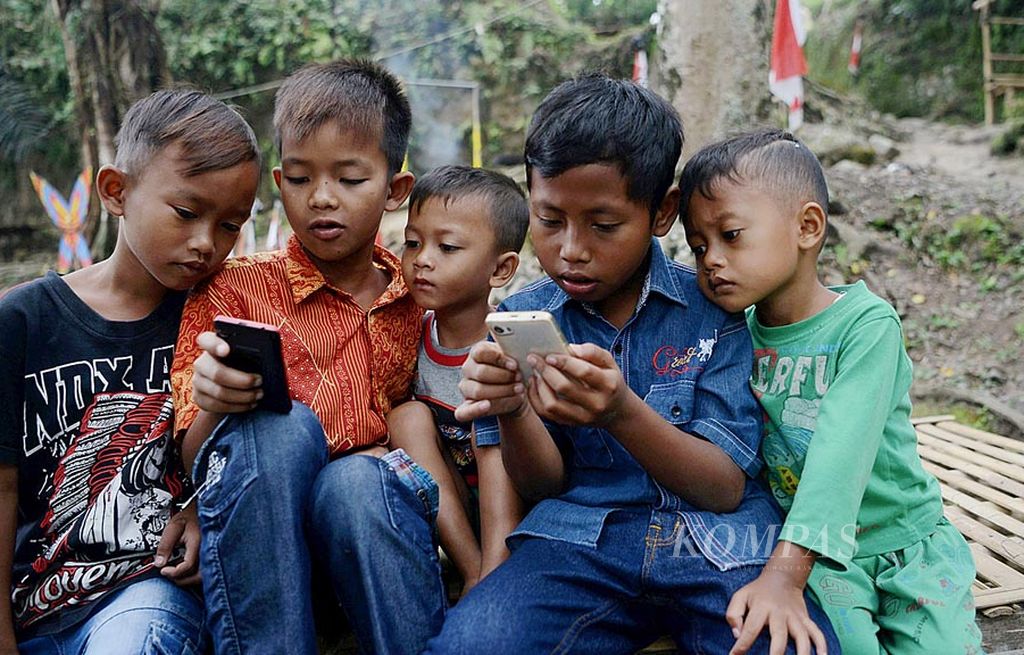 Anak-anak menggunakan gawai untuk bermain di Desa Socokangsi, Kecamatan Jatinom, Kabupaten Klaten, Jawa Tengah, Jumat (14/7). Perkembangan teknologi membuat mainan tradisional semakin tersisih dari kehidupan sehari-hari anak-anak. Penggunaan gawai yang berlebihan juga berdampak terhadap kesehatan mata. 