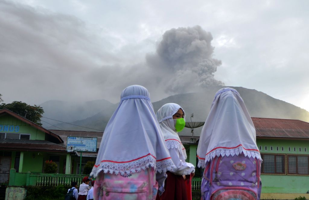 Sejumlah murid SD berada di depan sekolahnya sebelum ujian saat Gunung Marapi mengeluarkan abu vulkanik di Nagari Batu Palano, Agam, Sumatera Barat, Senin (4/12/2023). 