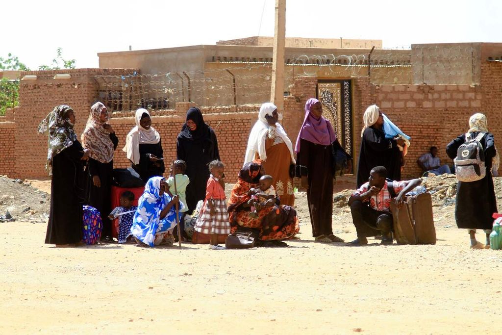 Sejumlah warga menunggu angkutan untuk keluar dari Khartoum di wilayah selatan Khartoum, 21 April 2022.Pertempuran sengit antara dua faksi militer telah menewaskan lebih dari 400 orang dan melukai ribuan orang. Ribuan warga kota Khartoum berusaha mengungsi keluar kota. (Photo by Ebrahim Hamid / AFP)