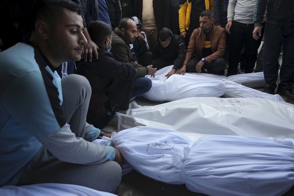 Warga Palestina menyelanggarakan pemakaman untuk keluarga dan kerabat mereka yang tewas dalam serangan bom Israel di Jalur Gaza, di Deir al Balah, Kamis (21/12/2023).