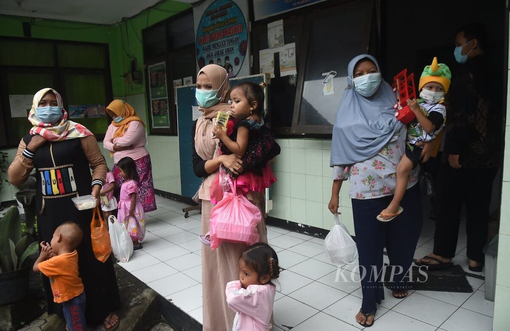 Ibu dan anak balitanya seusai mengambil makanan gratis program Gerakan Masyarakat Peduli Anak Stunting di Kantor Kelurahan Asemrowo,  Surabaya, Jawa Timur, Jumat (3/12/2021). 