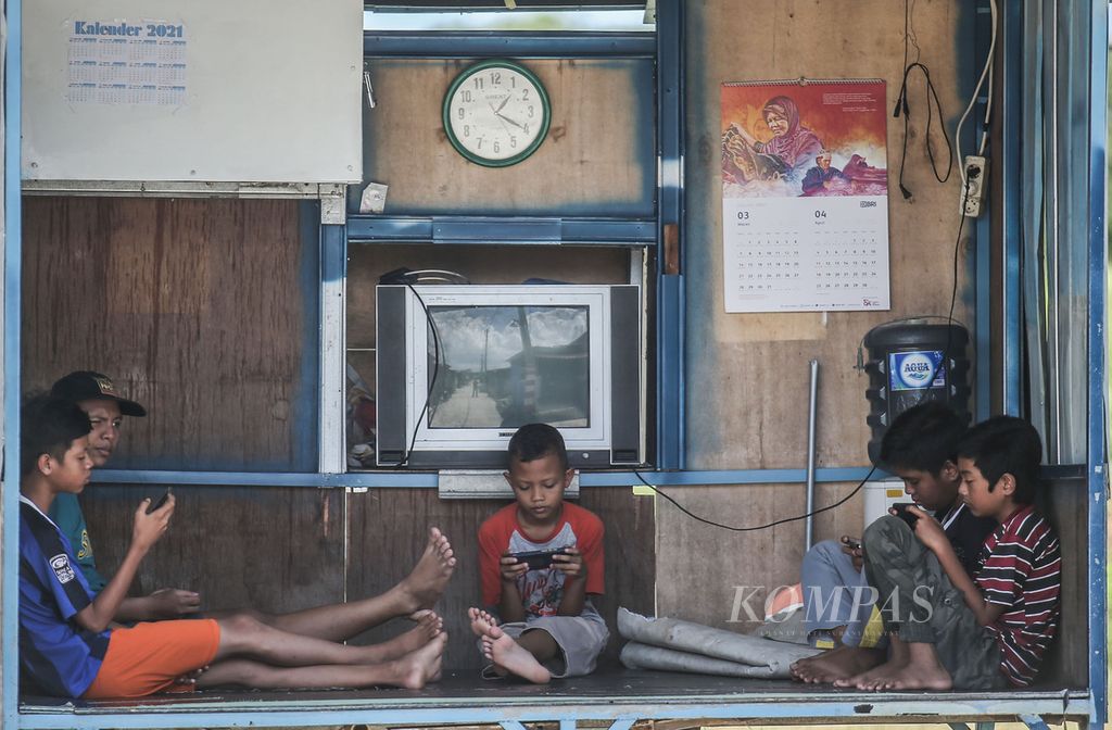 Children are playing online games at a guard post in the Cibunar area of Bogor, West Java, on Sunday (21/3/2021). Based on a survey by the Indonesian Child Protection Commission of 25,264 children from 34 provinces in Indonesia, during the pandemic, 76.8 percent of children were allowed to use gadgets for purposes other than learning. They use gadgets for chatting, watching YouTube, searching for information, social media, and so on.