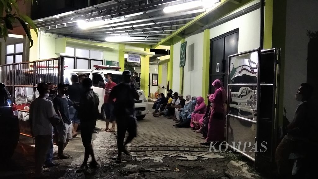 Pihak keluarga menunggu di luar instalasi forensik dan perawatan jenazah RSUD dr Soebandi, Jember, Jawa Timur, saat berlangsung pemeriksaan jenazah anggota keluarga mereka yang menjadi korban kecelakaan laut di Pantai Payangan, Minggu (13/2/2022) malam.