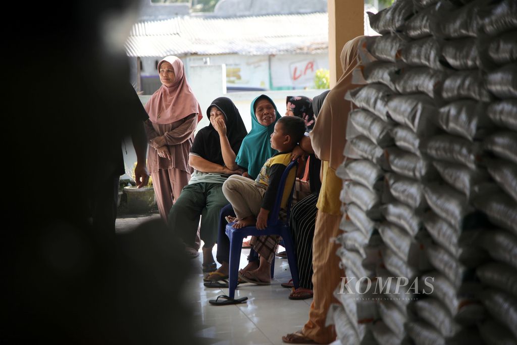 Warga menunggu pembagian beras di kantor Desa Pringgasela Selatan, Kecamatan Pringgasela, Kabupaten Lombok Timur, Nusa Tenggara Barat, Senin (18/12/2023). Mereka yang menerima bantuan sosial nontunai ini merupakan keluarga penerima manfaat Program Keluarga Harapan (PKH). 