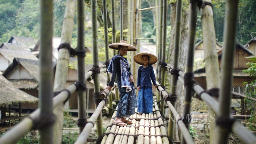 Ana (left) and Mila wait for their friends to cross a bamboo bridge in Gajeboh Village, Kanekes Village, Leuwidamar District, Lebak Regency, Banten, Thursday (16/3/2023). The Baduy people live peacefully with simplicity.