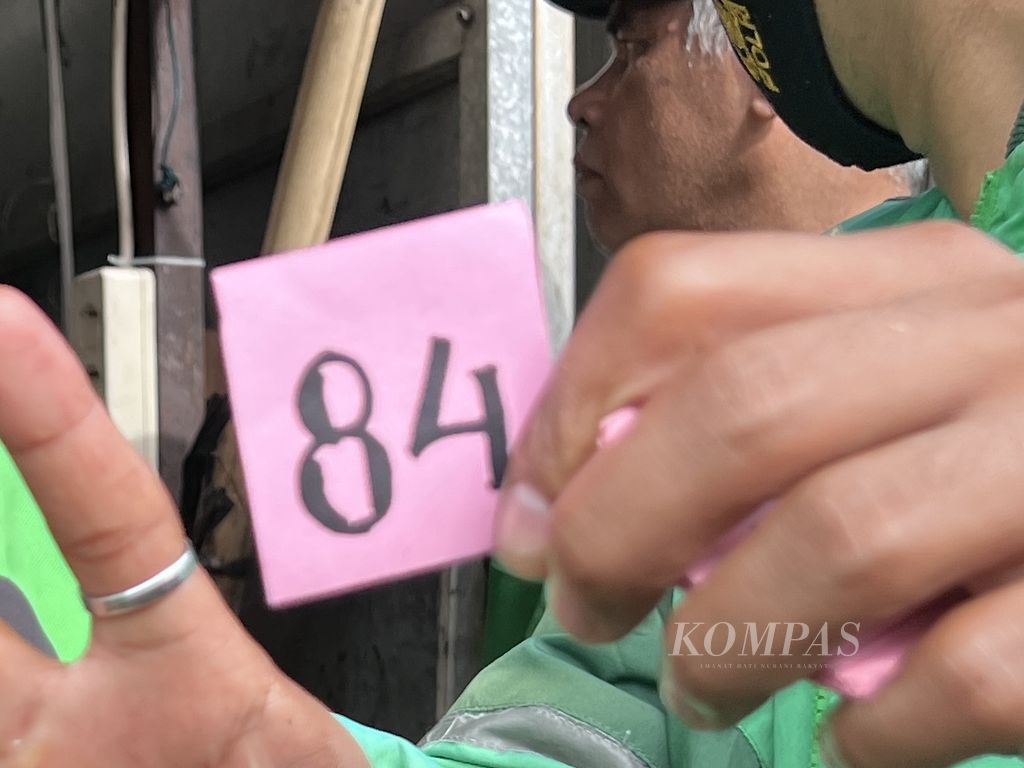 Seorang kurir yang melayani pemesanan makanan via daring menunjukkan nomor antrean di salah satu toko jalangkote di Jalan Tamalate, Kota Makassar, Selasa (12/3/2024). 