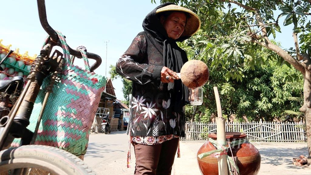 Taniah (50), pedagang telur asin keliling, meminum air dari dalam gentong di Desa Suranenggala, Kecamatan Suranenggala, Kabupaten Cirebon, Jawa Barat, Rabu (17/7/2019).