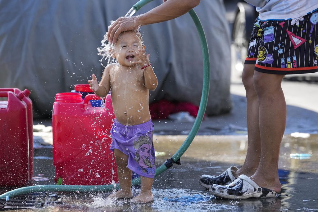Seorang anak diguyur air di tengah panas yang menyelimuti Manila, Filipina, 26 April 2024. 