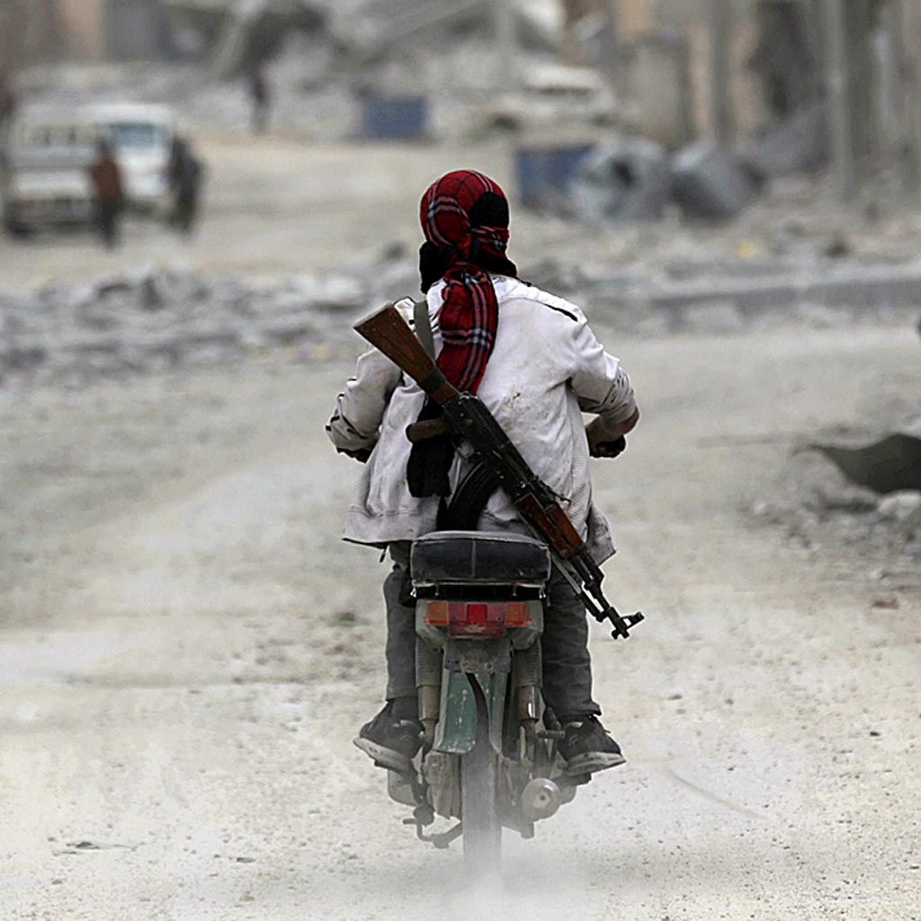 Seorang pria  menyandang senapan mengendarai motor melewati jalan dengan gedung-gedung yang hancur di Al Bab, Suriah utara, Rabu (1/3).