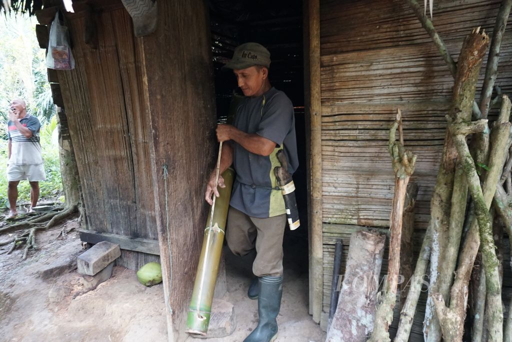 Nurdin Maletang, seorang petani gula aren, mengambil tabung penampung nira untuk diletakkan di bawah mayang pohon aren, Selasa (19/7/2022), di perkebunan rakyat Desa Tapa Aog, Lolayan, Bolaang Mongondow, Sulawesi Utara.