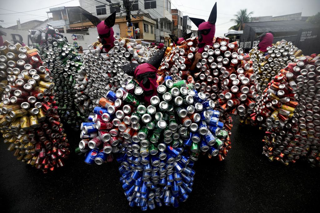 Warga menggunakan kostum yang disebut sebagai <i>pierro</i>, kostum yang dibuat dari serangkaian kaleng bekas minuman, di karnaval jalanan yang diselenggarakan di Kota Madre de Deus, Brasil, Minggu (11/2/2024).  