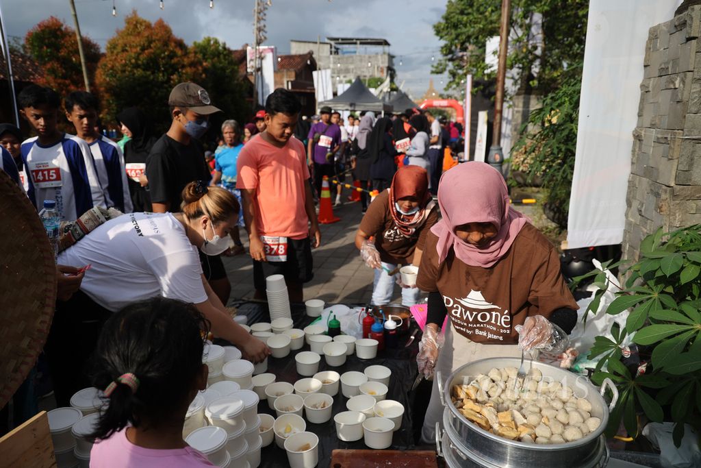 Anggota kelompok UMKM Pawone menyajikan produk mereka kepada pelari peserta ajang Borobudur Marathon Fun Run 2022 di kawasan sekitar Candi Pawon, Desa Wanurejo, Kecamatan Borobudur, Kabupaten Magelang, Jawa Tengah, Minggu (11/12/2022). 
