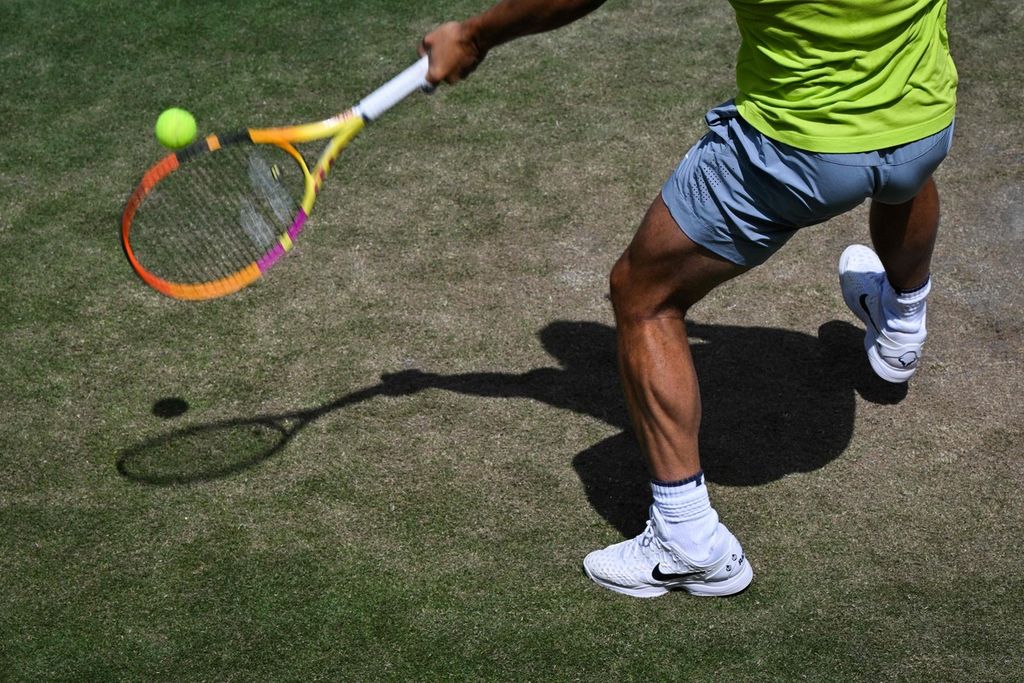 Rafael Nadal memukul bola saat berlatih di kompleks All England Tennis Club, Wimbledon, London, Minggu (26/6/2022). Cedera telapak kaki kiri sempat mengancam Nadal batal tampil pada Wimbledon kali ini. 
