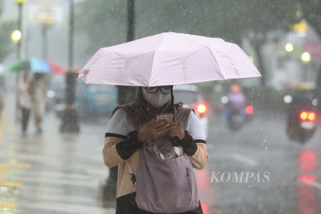 Warga menggunakan ponsel saat hujan deras di Jalan Margonda, Kota Depok, Jawa Barat, Sabtu (13/1/2024). Hujan deras disertai petir mengguyur Kota Depok pada Sabtu sore. Kilat yang menyambar-nyambar membuat sejumlah warga memilih untuk berteduh di sejumlah pertokoan. 