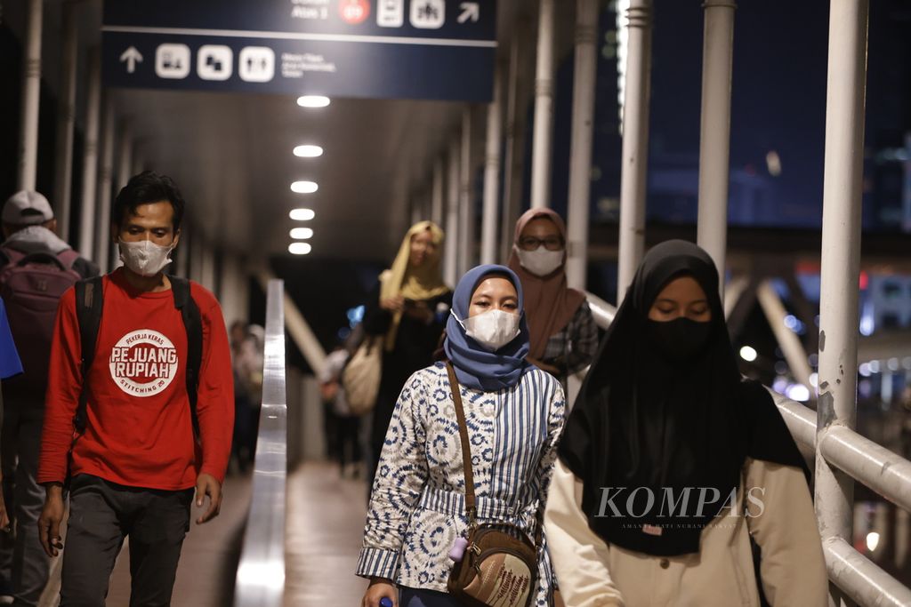 Warga mengenakan masker saat berjalan di atas jembatan penyeberangan orang di kawasan Dukuh Atas, Jakarta, Jumat (15/12/2023).  