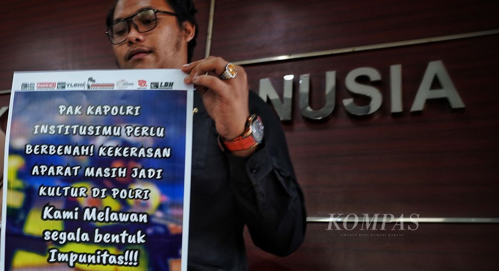 Koordinator LBH Pos Malang Daniel Siagian membawa poster saat mendampingi keluarga korban Tragedi Stadion Kanjuruhan mendatangi kantor Komisi Nasional Hak Asasi Manusia (Komnas HAM), Jakarta, Selasa (11/4/2023). 