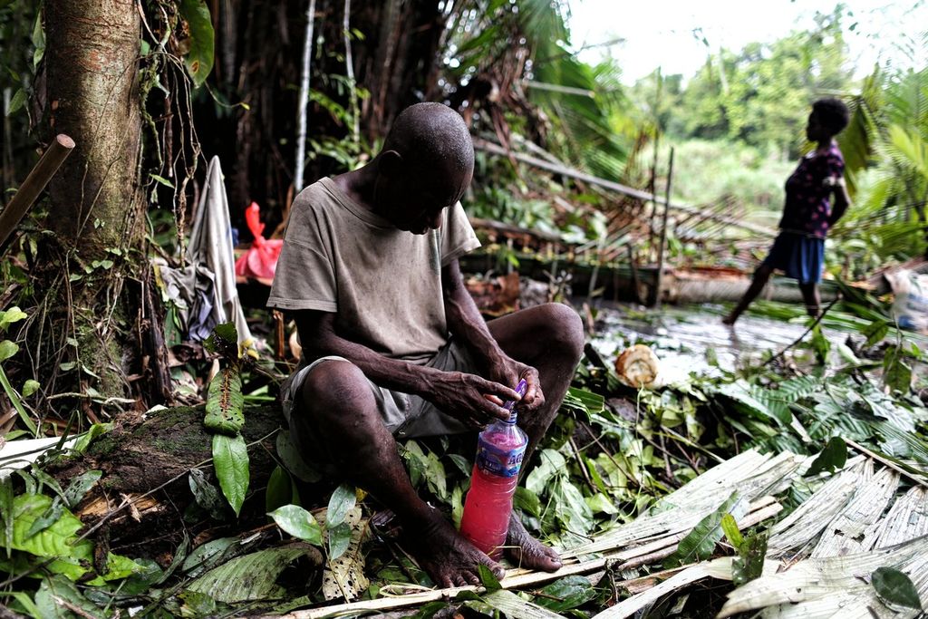 Yoris mencampurkan minuman saset berenergi ke dalam botol yang telah ia isi dengan air sungai saat bersama warga Kampung As dan Atat, Distrik Pulau Tiga, Asmat, Papua, memangkur sagu di hutan adat mereka, Kamis (14/10/2021).
