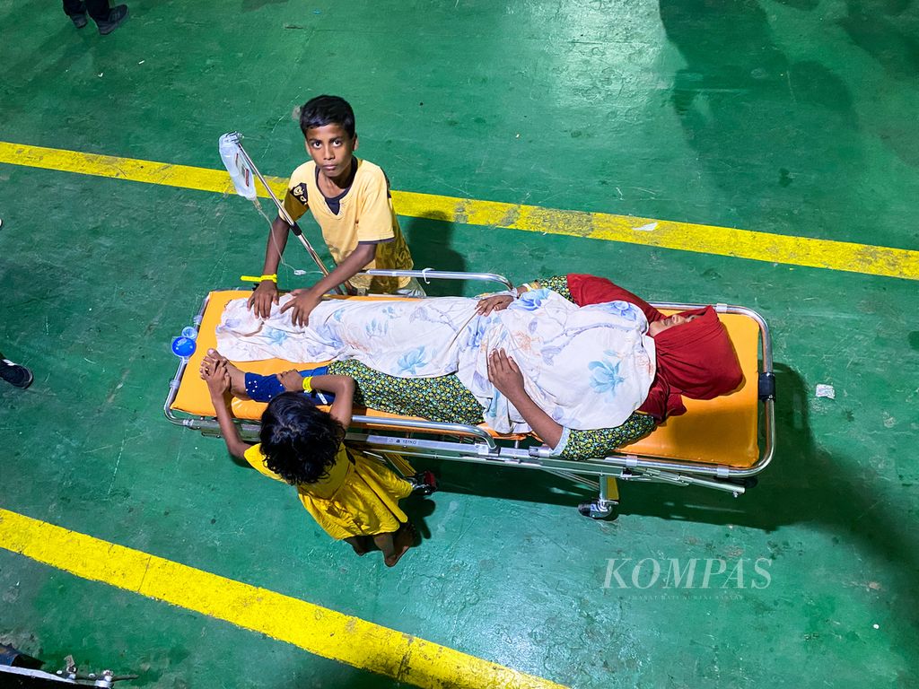 Two Rohingya refugee children take care of their sick mother upon arriving at Ulee Lheu Port in the city of Banda Aceh, Aceh Province, on Wednesday (22/11/2023).