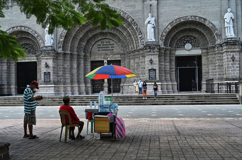 Seorang pedagang asongan menanti pelanggan di depan Katedral Manila di Manila, Filipina, Rabu (11/5/2022). 