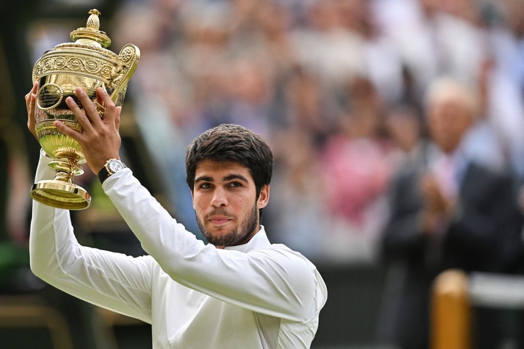 Petenis Spanyol, Carlos Alcaraz, mengangkat trofi sebagai juara Grand Slam Wimbledon 2023 setelah mengalahkan Novak Djokovic dalam laga final di All England Tennis Club, London, Inggris, 16 Juli 2023. 
