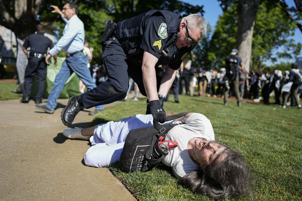 Seorang petugas polisi menahan seorang demonstran di kampus Emory University dalam unjuk rasa pro-Palestina, Kamis (25/4/2024) di Atlanta, Amerika Serikat. 