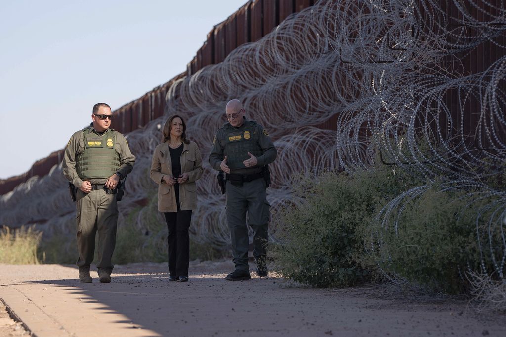 Calon presiden AS dari Partai Demokrat, Kamala Harris (tengah), berjalan di dekat pagar yang membatasi wilayah AS dan Meksiko di Douglas, Arizona, Kamis (27/9/2024). Harris ingin memperketat pemberian suaka dan penerimaan imigran yang masuk ke AS. 