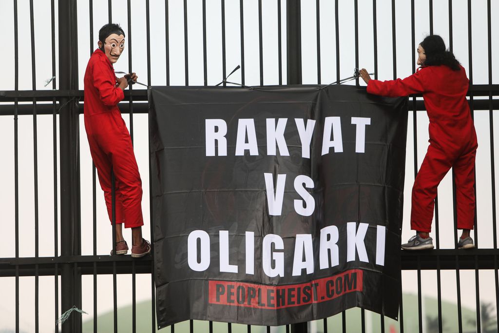 Spanduk yang dibawa aktivis yang tergabung dalam People Heist saat berunjuk rasa di depan Gedung Parlemen, Senayan, Jakarta, Senin (4/10/2021). 