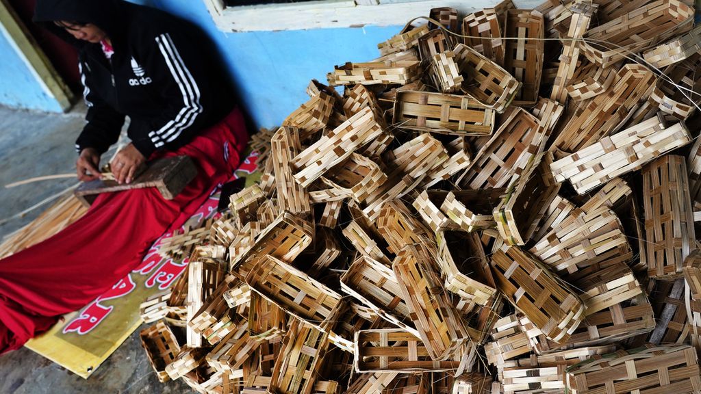 Rinta (26) menyelesaikan pembuatan keranjang besek bambu untuk ikan pindang di depan rumahnya di Kampung Pasir Pogor, Cijeruk, Kabupaten Bogor, Jawa Barat, Rabu (24/2/2021). 