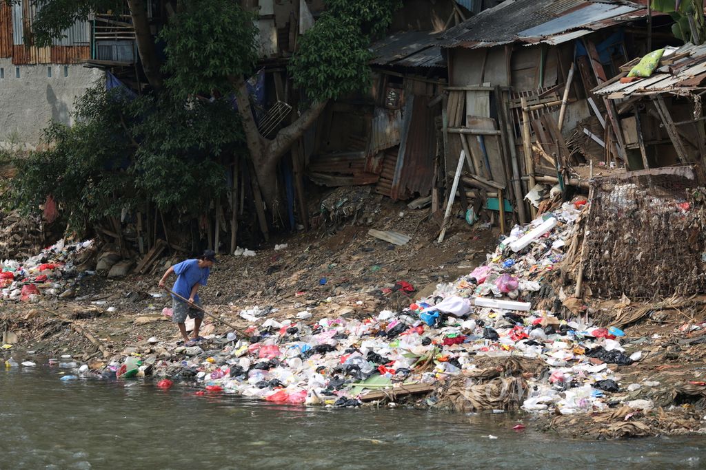 Warga mendorong sampah yang menumpuk di bantaran Sungai Ciliwung di Bidara Cina, Jatinegara, Jakarta Timur, Selasa (25/7/2023). 