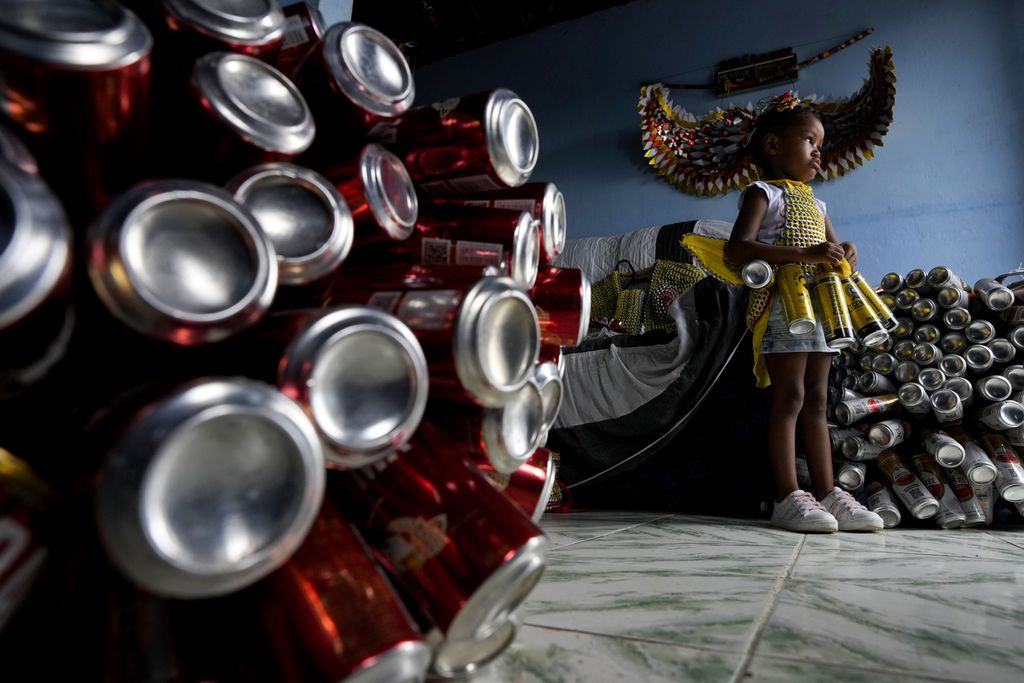 Seorang anak perempuan berdiri di dekat <i>pierro</i>, kostum yang terbuat dari kaleng aluminium bekas minuman bir dan soda, di sebuah rumah di Kota Madre de Deus, Brasil, Minggu  (11/20/2024). 